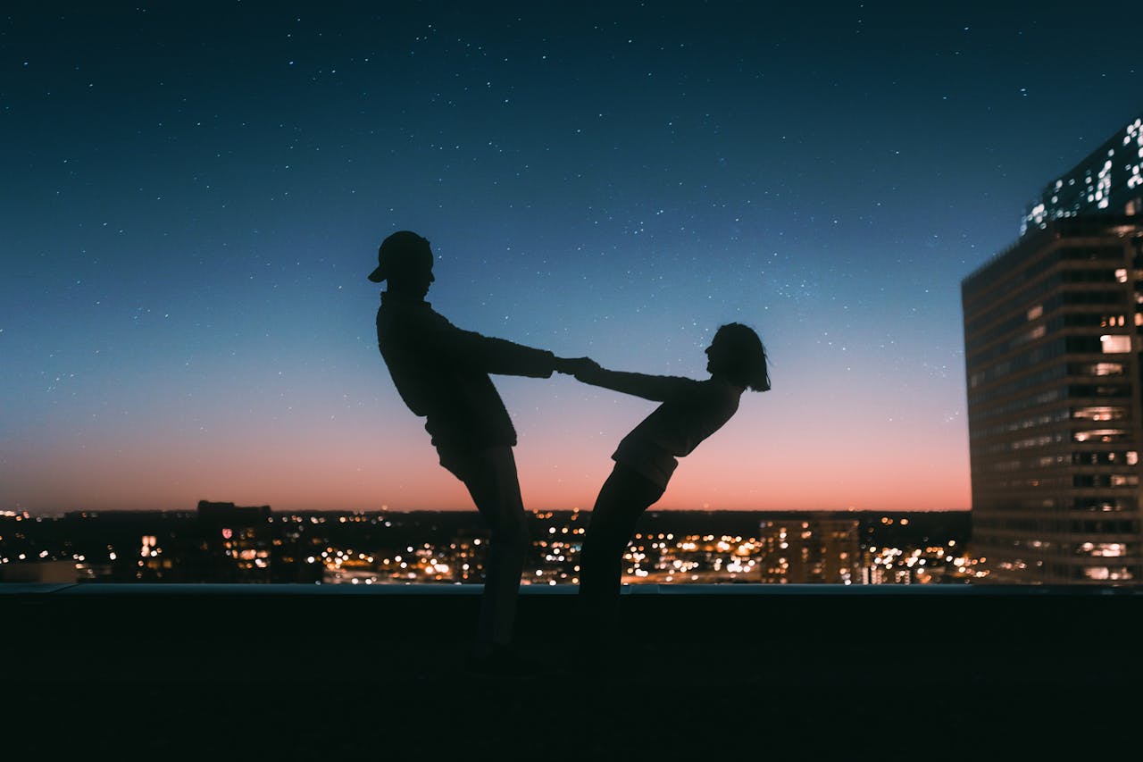 about-01 A couple silhouetted against a starry sky on a rooftop in Minneapolis at sunset.