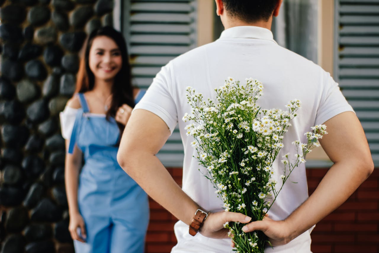 our-services-3 A man surprises his partner with flowers behind his back, symbolizing love and romance.